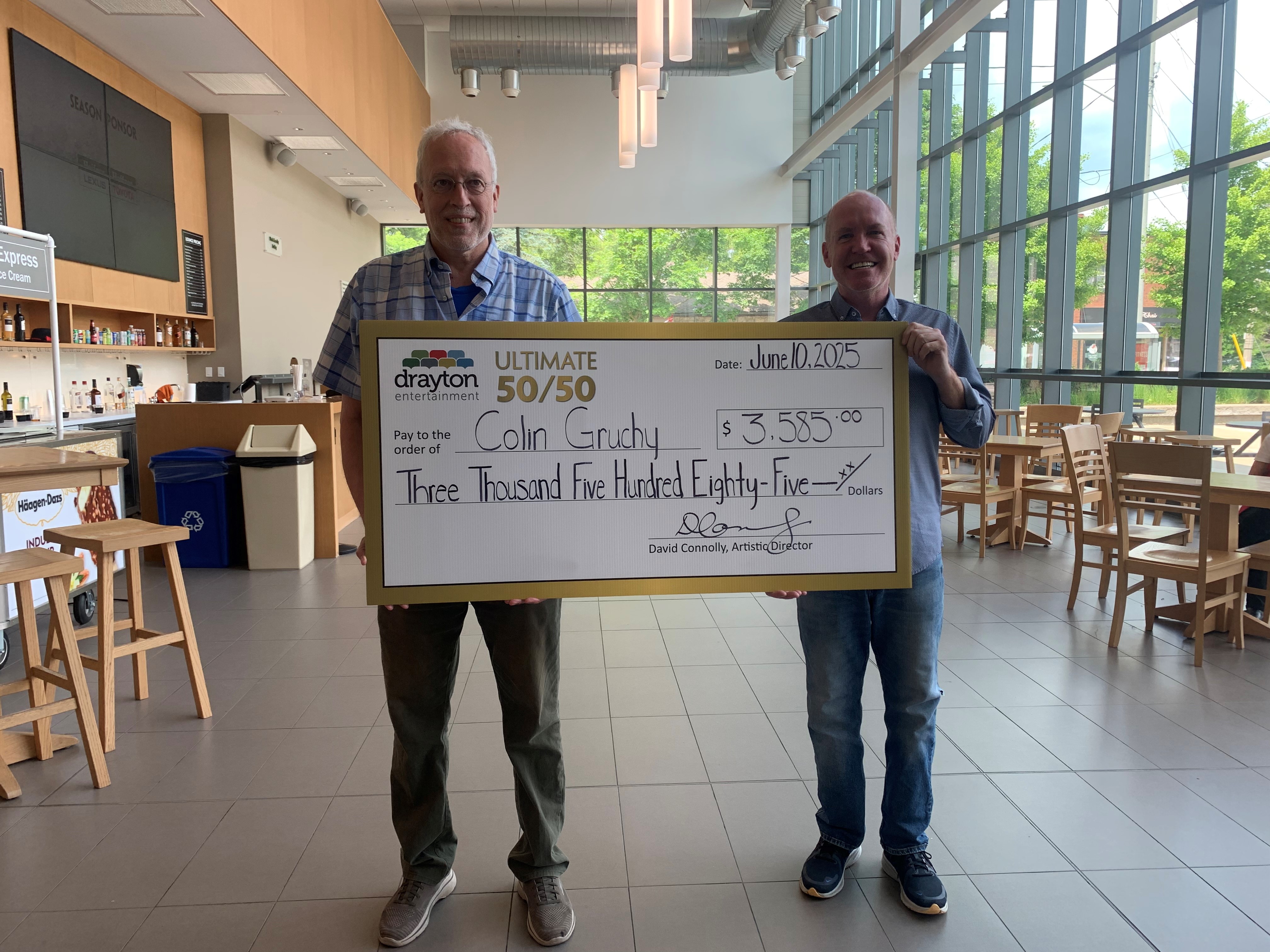 Colin Grunchy (left) is pictured holding a large presentation cheque for $3,585 alongside Drayton Entertainment Artistic Director David Connolly (right). The cheque, dated June 10, 2025, celebrates Colin as the winner of the Ultimate 50/50 draw. The 